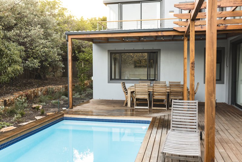 Patio exterior con muebles de madera y piscina, ambiente moderno.